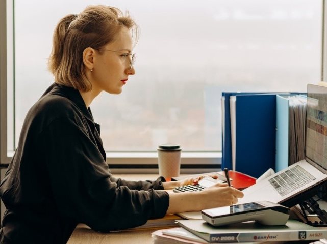kobieta siedzi przed laptopem i pracuje w skupieniu