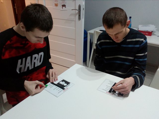 dwóch młodych mężczyzn w mieszkaniu treningowym siedzą przy stole i pracują nad grafikiem