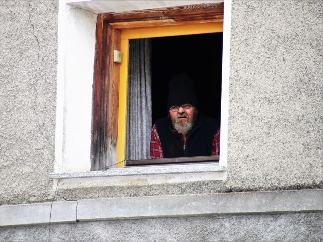 mężczyzna wygląda przez okno starej kamienicy