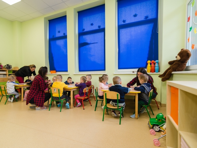 dzieci i nauczycielki w sali pracują w grupach przy stolikach