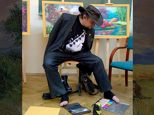 Stanisław Kmiecik maluje stopami obraz na podłodze galerii obrazów