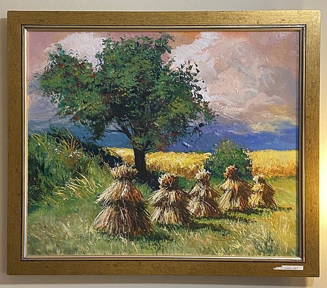 Obraz wiszący na ścianie przedstawiający snopki siana, w tle drzewo i pole