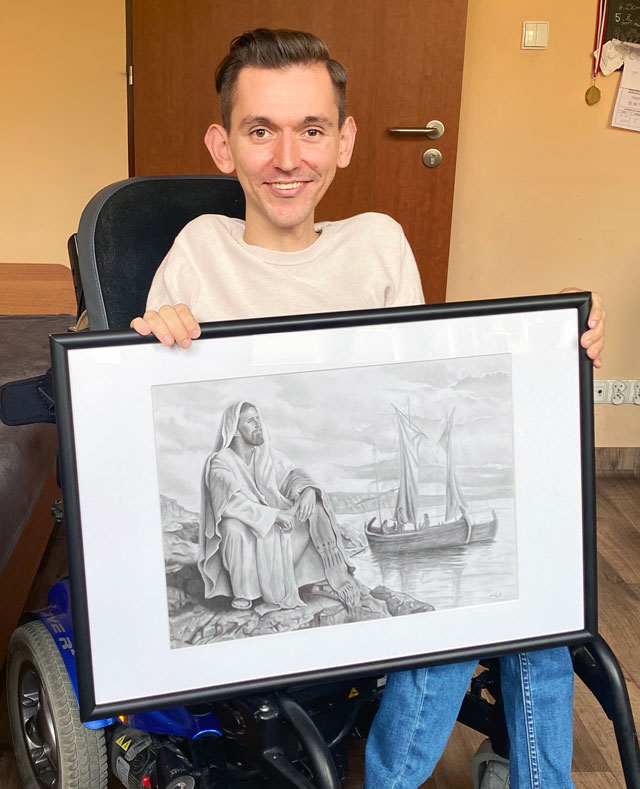 Patryk Kleinschmidt trzyma swój obraz, na którym Jezus siedzi na brzegu jeziora, w tle łódź.