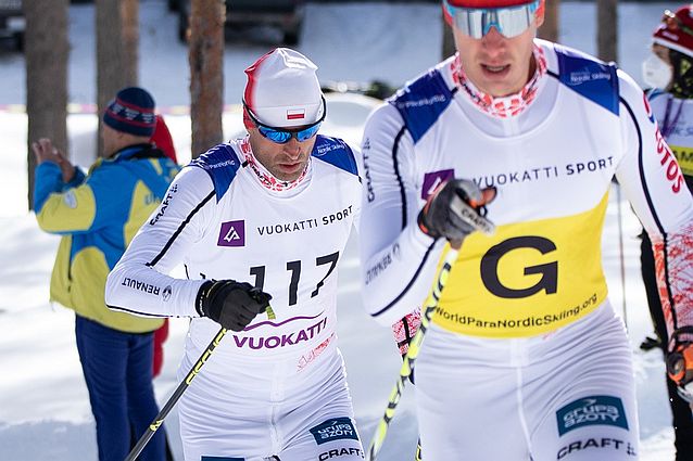 Piotr Garbowski biegnie na nartach, przed nim biegnie na nartach jego przewodnik