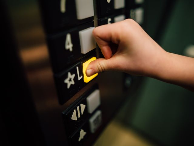 ręka osoby w windzie naciskająca przycisk