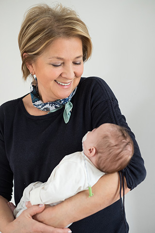 Joanna Bobińska szeroko uśmiecha się do niemowlęcia, które trzyma na rękach