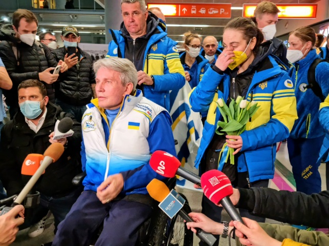 ukraińscy sportowcy stoją obok siebie, mówią do mikrofonów. Są na hali przylotów na lotnisku w Warszawie