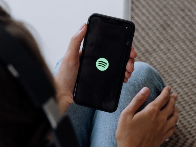 zbliżenie na telefon z aplikacją Spotify. Telefon trzyma kobieta