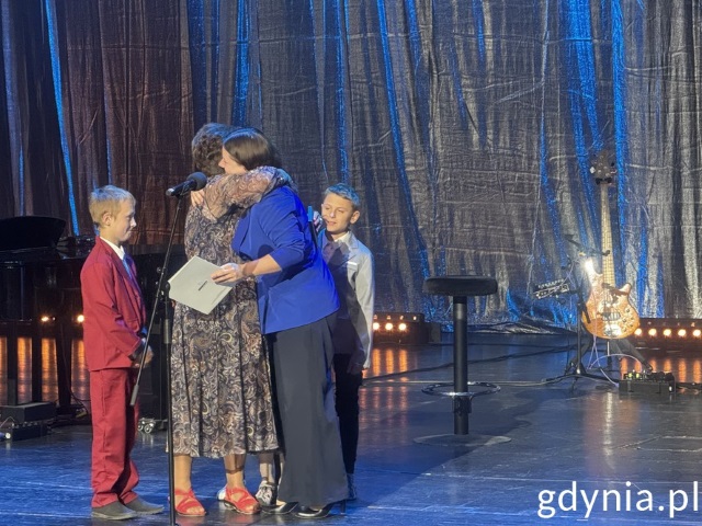 Prezydentka Alekandra Kosiorek przytula tegorczną laureatkę Barbarę Hurko, obok stoi dwóch małych chłopców. 