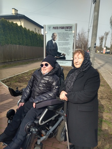 Wojciech Kowalczyk z mamą Haliną Pawłowską na tle tablicy Piotra Pawłowskiego
