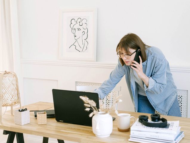 Kobieta rozmawia przez telefon i sprawdza pocztę w komputerze