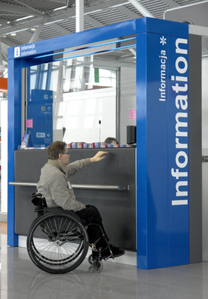 Mężczyzna na wózku na lotnisku przy stoisku z napisem 